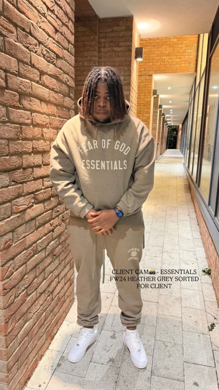 Client in a Fear of God Essentials hoodie and joggers in heather grey, in a brick walkway