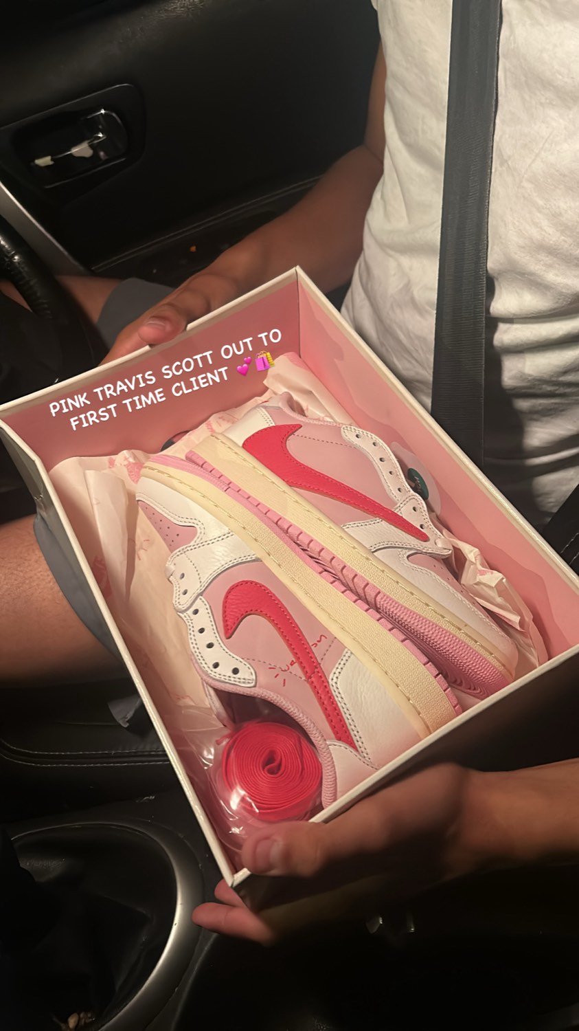 Pink Travis Scott sneakers in their box, held up in a car